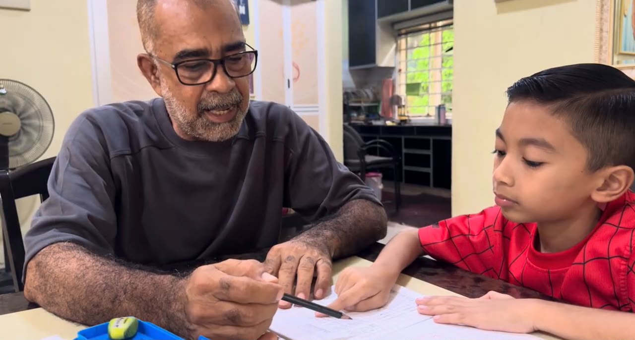 Lelaki warga emas mengajar seorang anak lelaki menulis