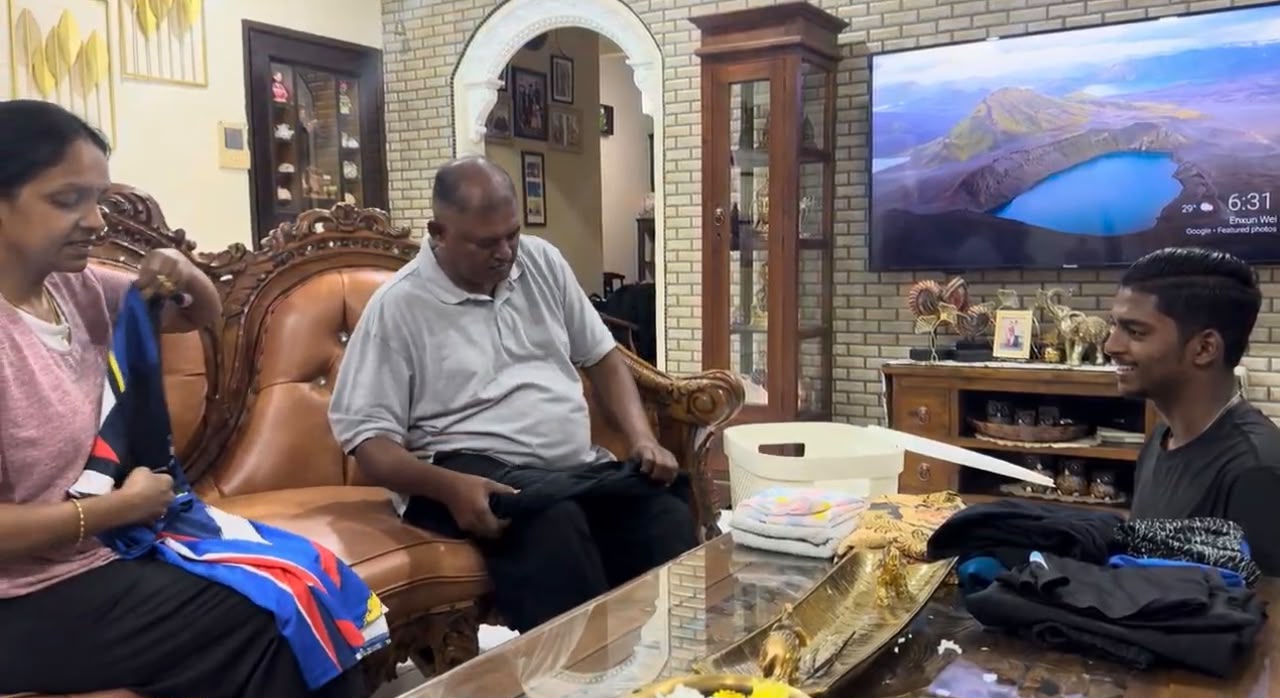 Seorang bapa melipat baju bersama keluarganya di ruang tamu